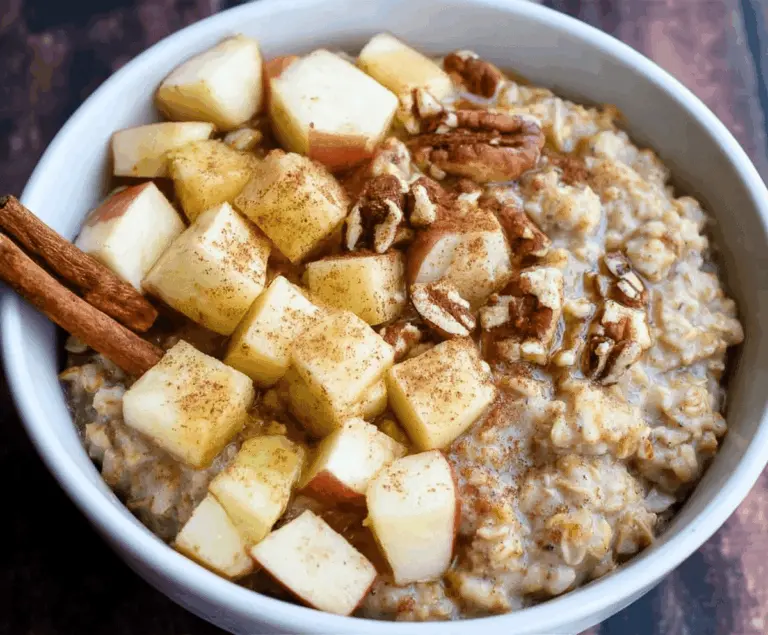 Creamy apple cinnamon oatmeal porridge topped with fresh sliced apples, cinnamon, and a drizzle of honey in a bowl.
