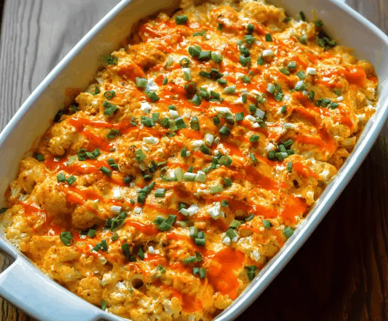 Creamy buffalo chicken cauliflower casserole topped with melted cheese and garnished with green onions, a healthy spicy comfort food option.