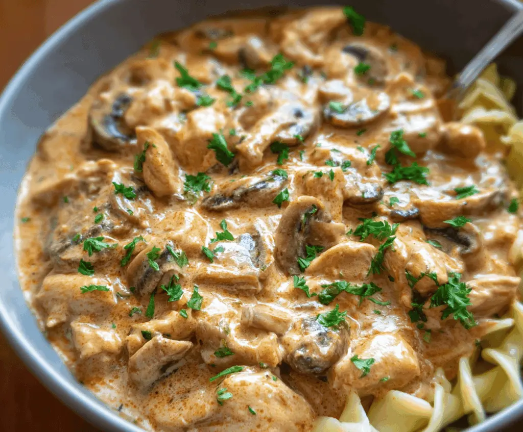 Creamy chicken stroganoff served over noodles with mushrooms and herbs, perfect for a comforting dinner.