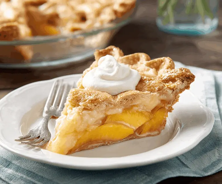 Delicious peaches and cream pie topped with fresh peach slices and creamy whipped topping on a rustic plate