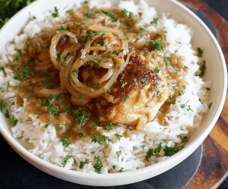 Delicious smothered chicken served over flavorful rice with gravy and garnished with fresh herbs