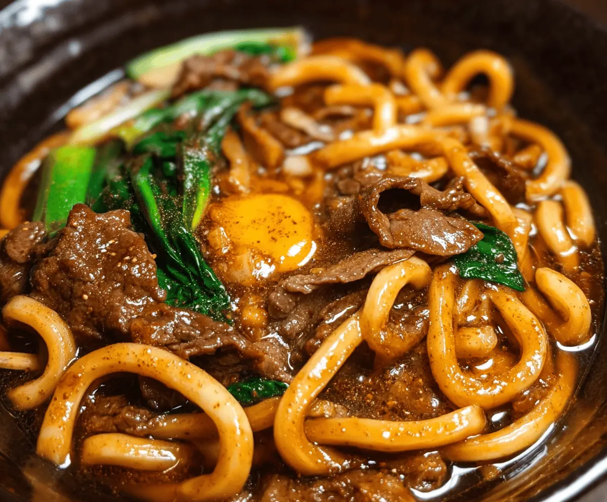 Savory beef black pepper udon noodles garnished with green onions on a plate