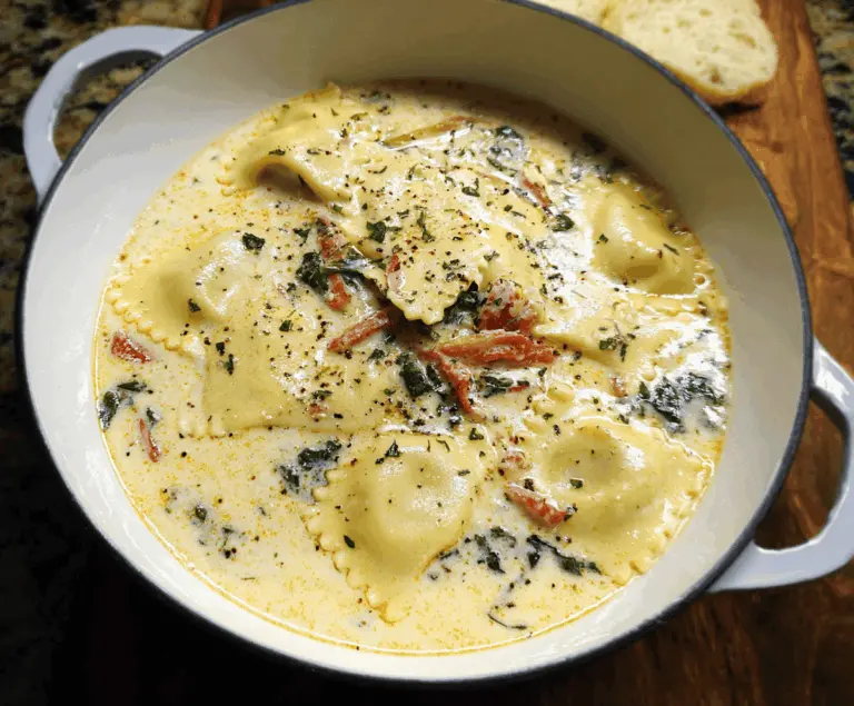 Creamy Tuscan Ravioli Soup with spinach, sun-dried tomatoes, and grated Parmesan cheese in a bowl