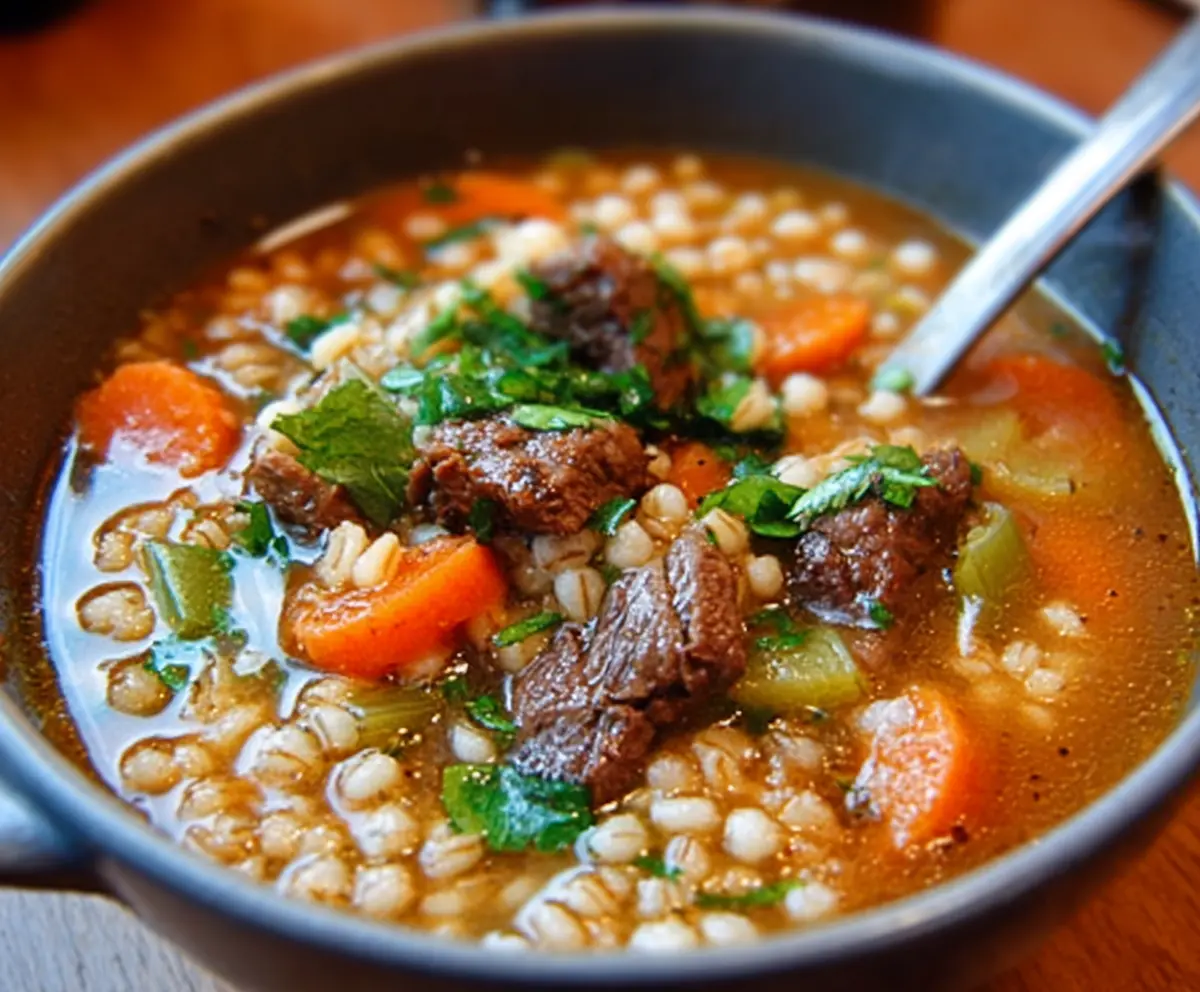 Hearty beef and barley soup in a rustic bowl, garnished with fresh herbs.