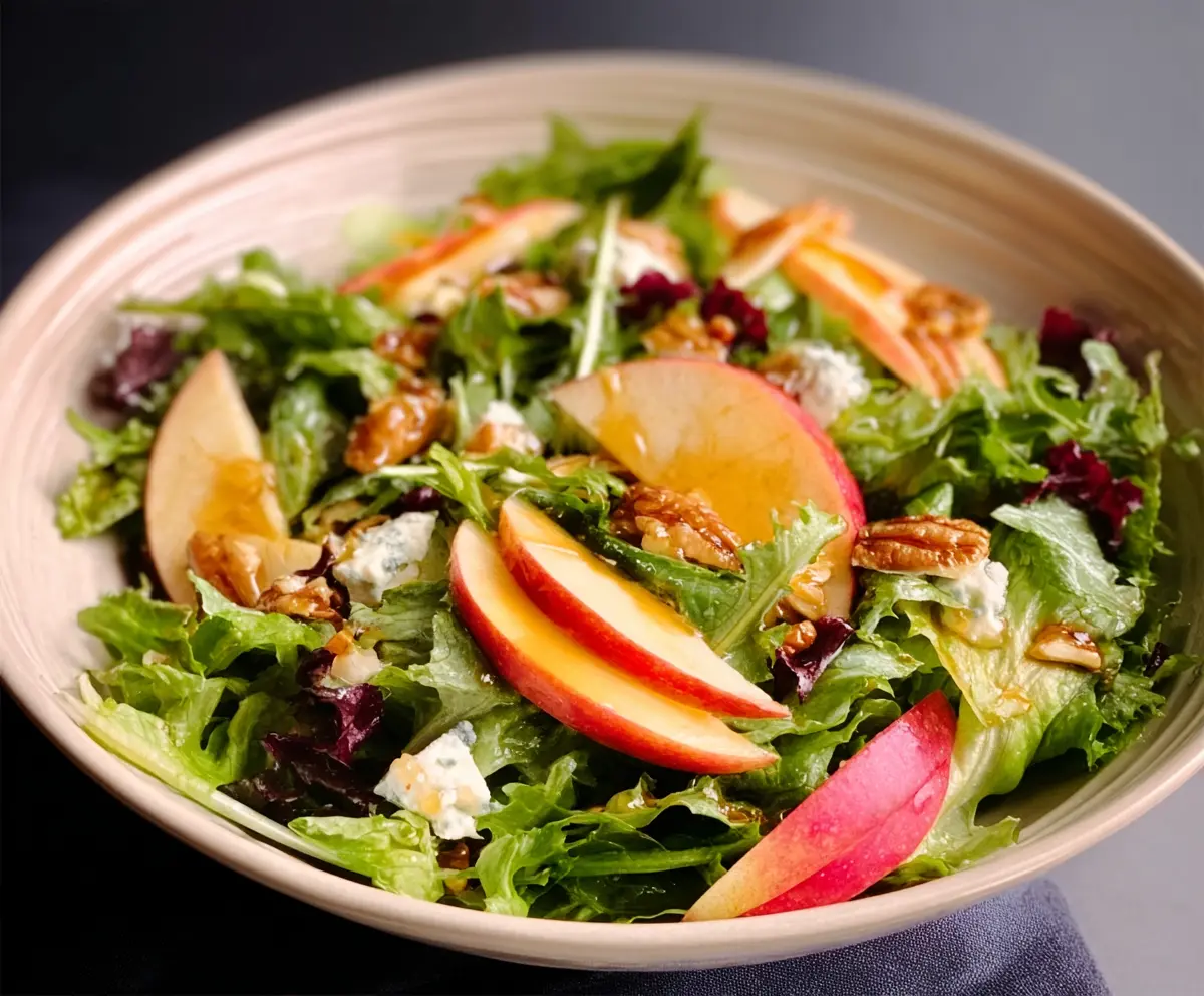 Fresh Honeycrisp salad with mixed greens and apple slices, topped with walnuts and drizzled with honey dressing.