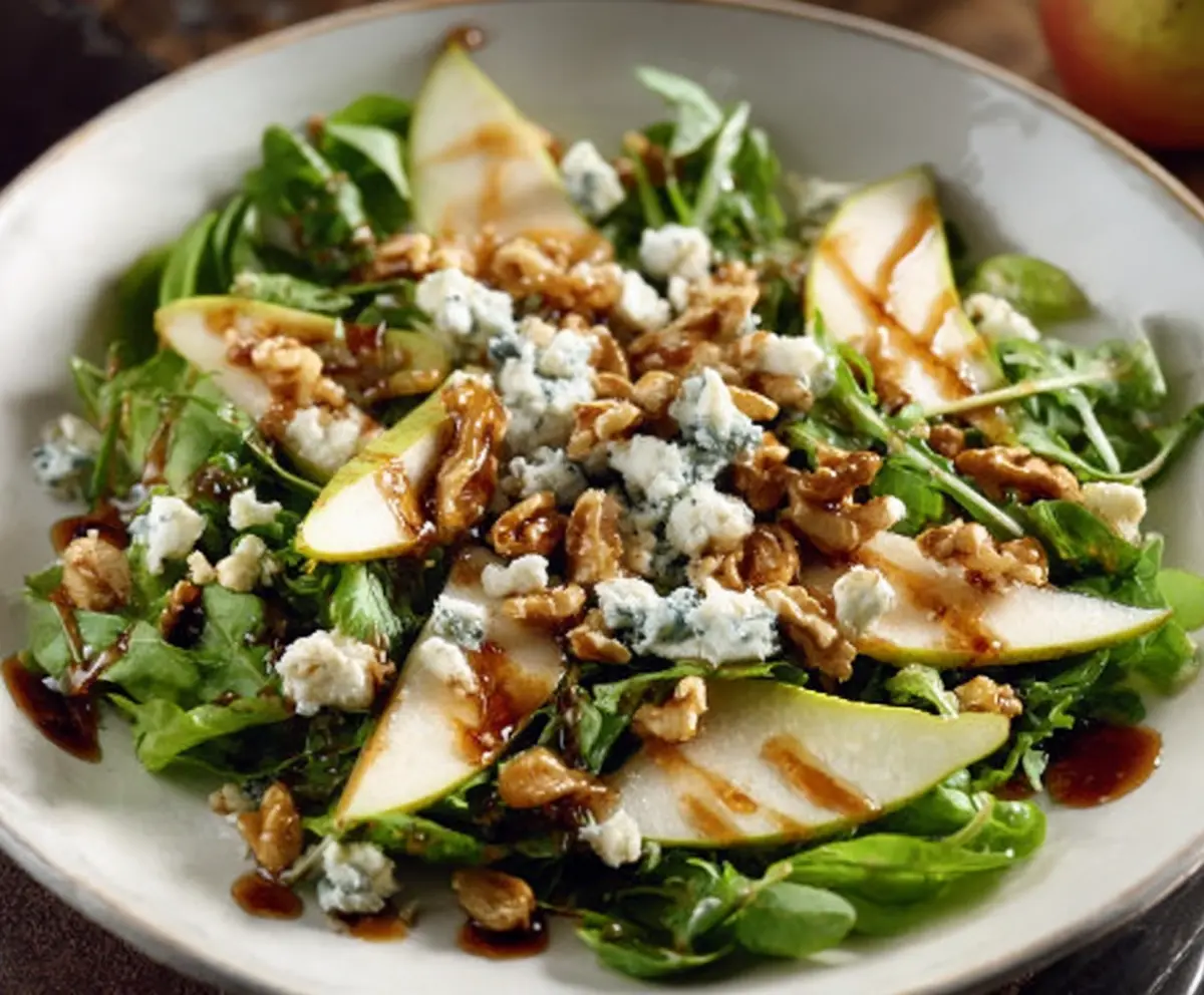 Fresh Pear and Gorgonzola Salad topped with Candied Walnuts on a rustic plate.