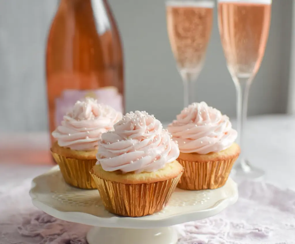 Delicious Rose Champagne Cupcakes with pink frosting and edible rose decorations for a celebration or special occasion.