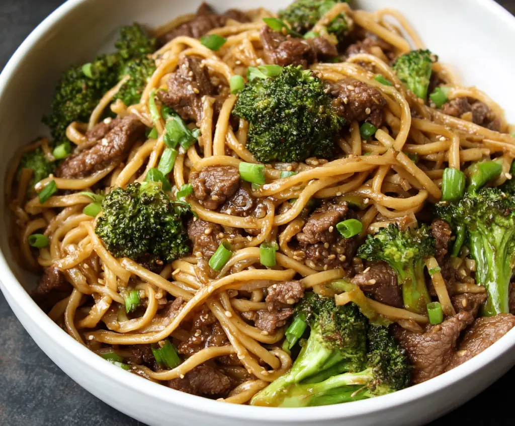 Delicious Garlic Ginger Beef and Broccoli Noodles served on a plate with fresh vegetables